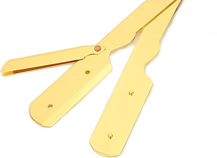 Gold-colored straight razors on a white background