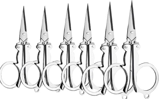Six pairs of silver metal scissors with circular finger rings, arranged side by side on a plain white background.