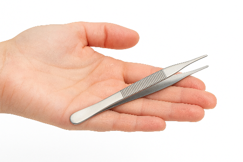 Metal tweezers held in a hand on a white background
